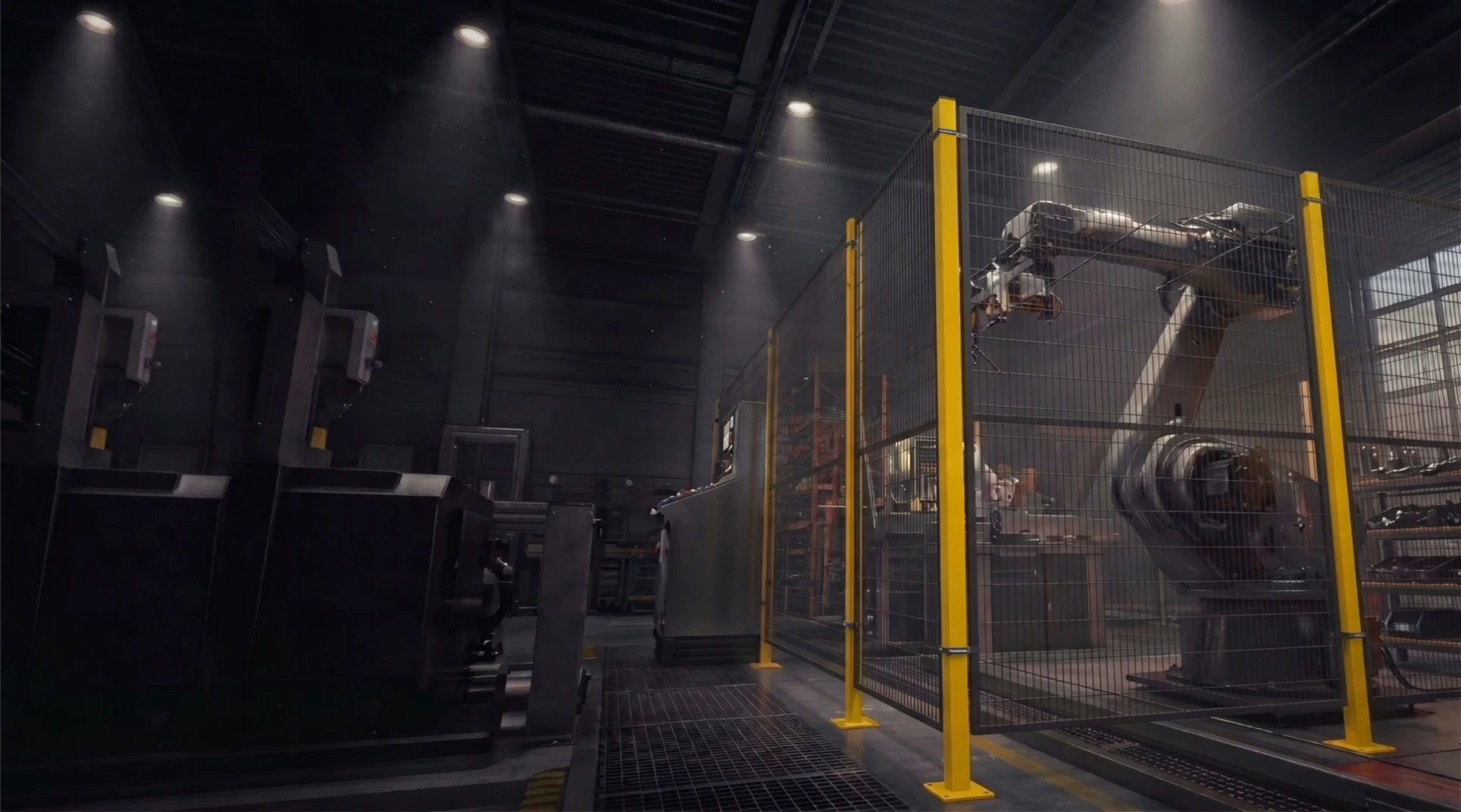Yellow-framed black wire-mesh machine guarding enclosing an industrial robot arm inside a dark factory hall